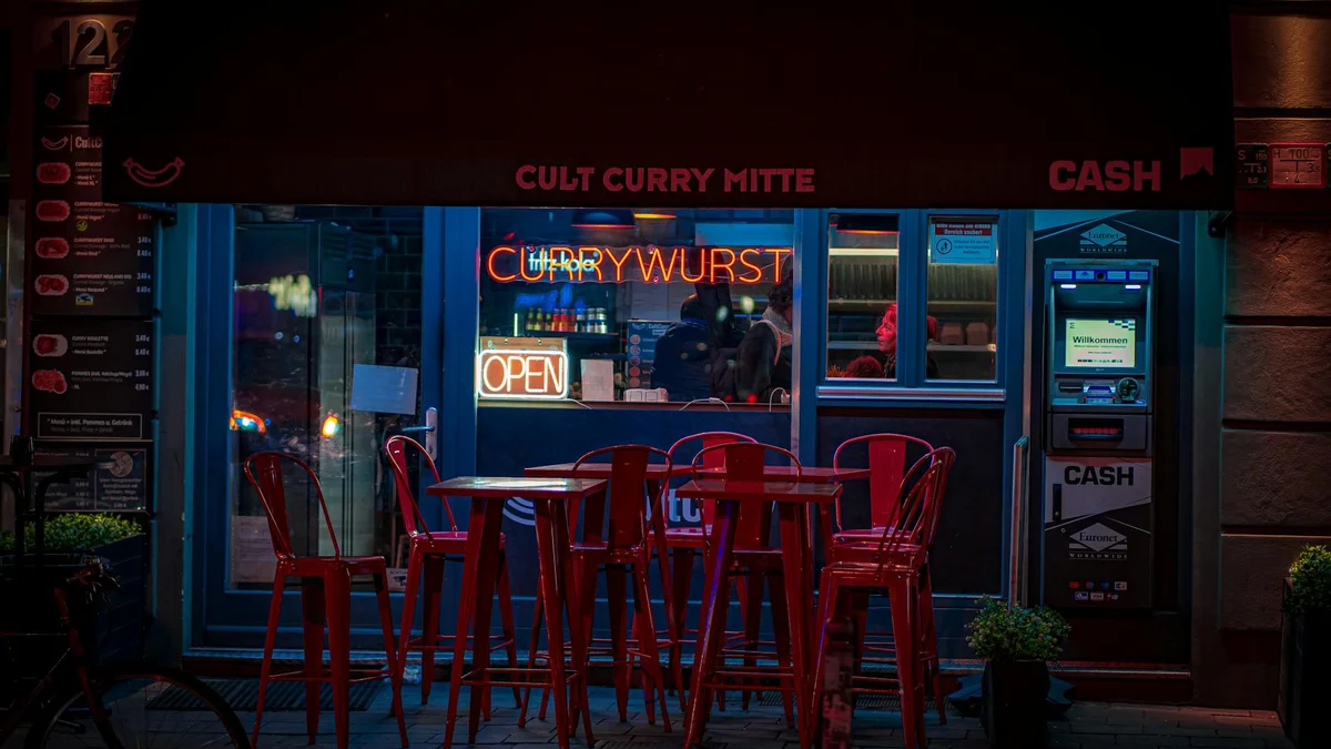 Currywurst clásica de Berlín troceada con salsa de curry y patatas fritas en bandeja de cartón